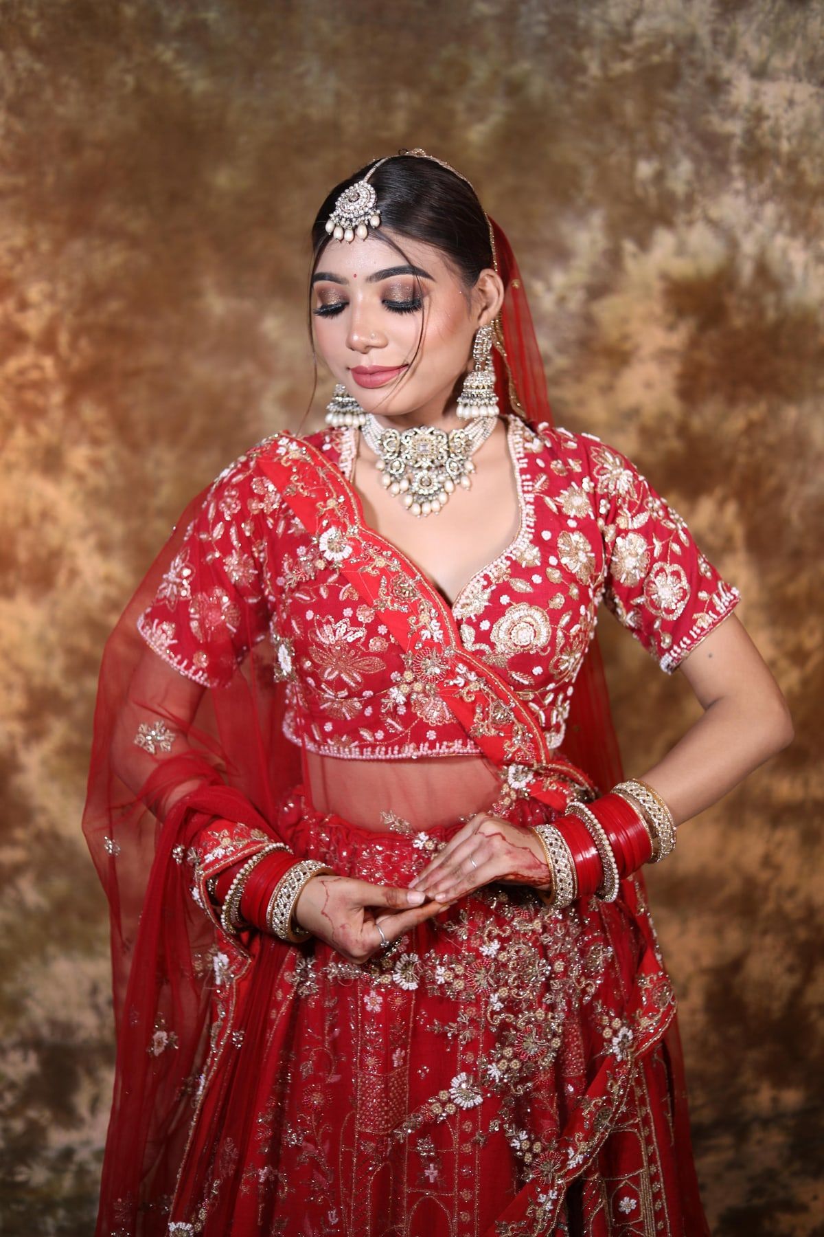 Classic North Indian bridal makeup with red dupatta and chooda